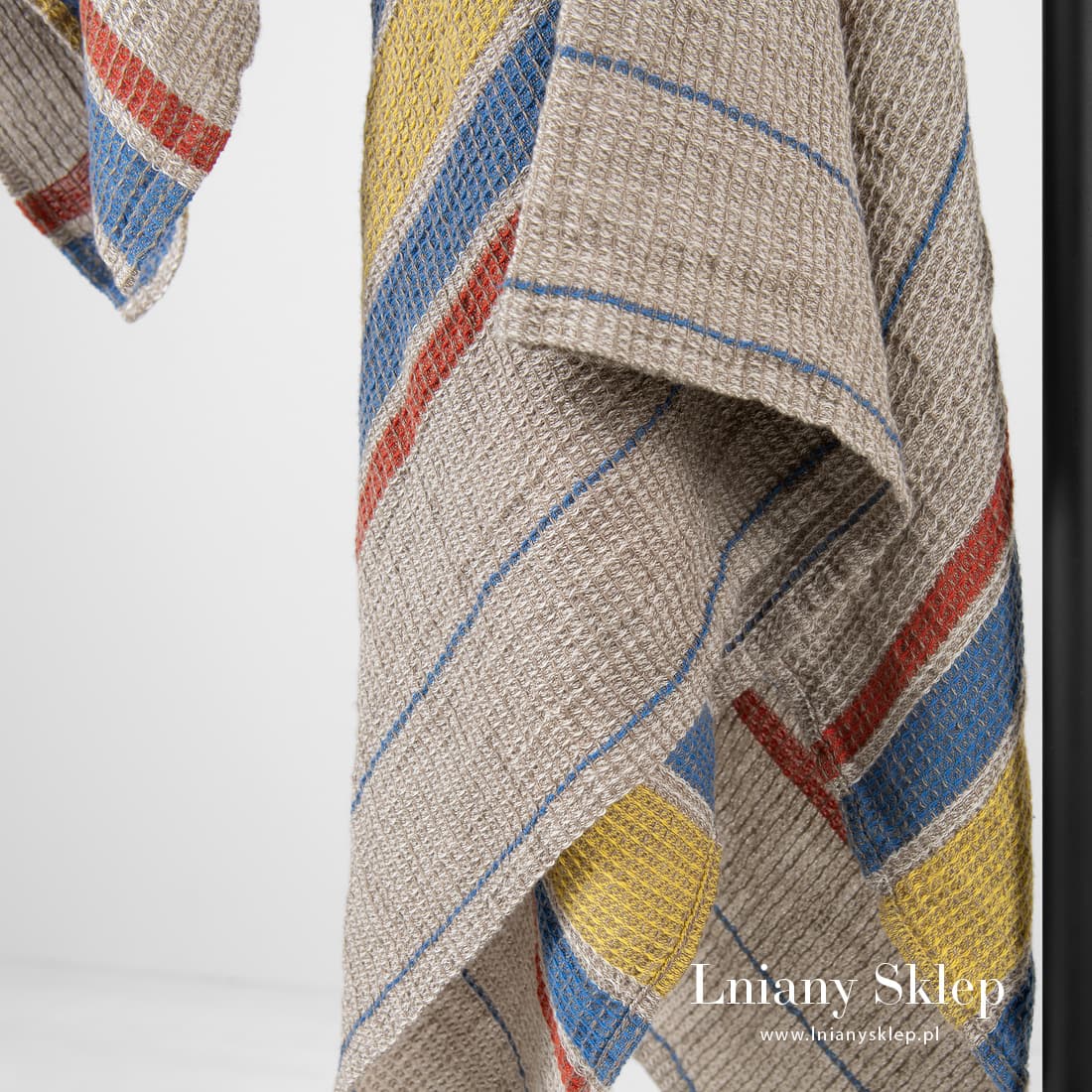 Szary w paski ręcznik z tkaniny waflowej.