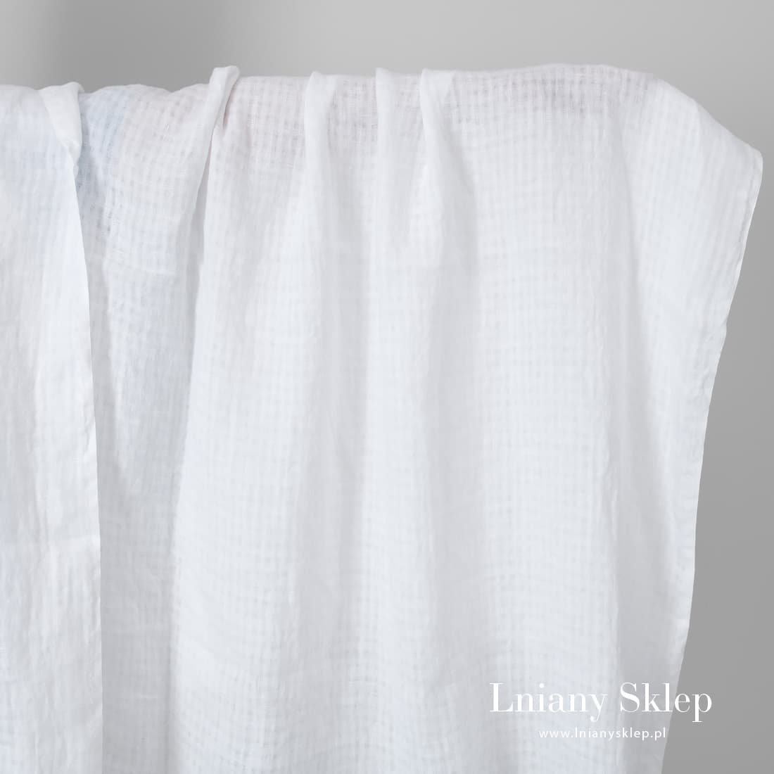 Biała w prześwitującą krateczkę tkanina lniana.