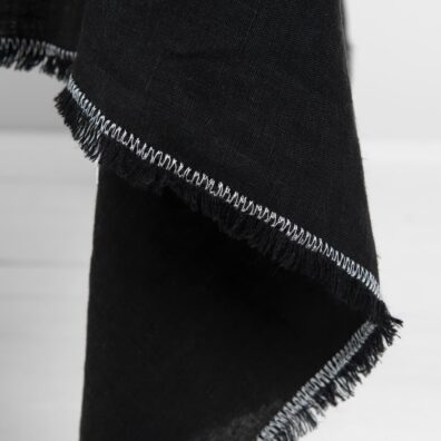 Prany obrus ozdobiony frędzelkami i mlecznobiałym ściegiem dekoracyjnym.