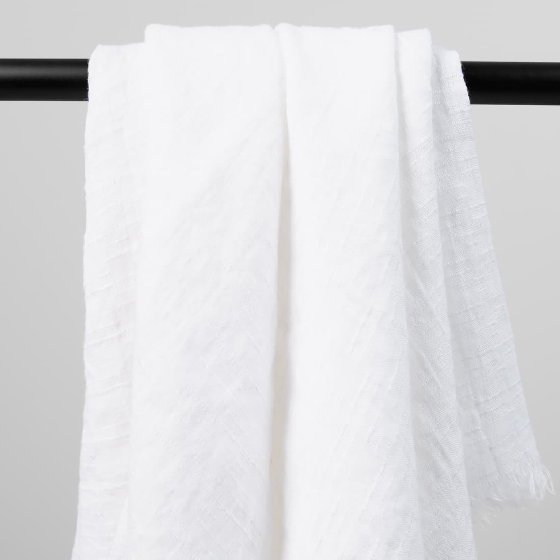 Chusta z białej, wytkanej w lekko wypukłe prążki pranej tkaniny.