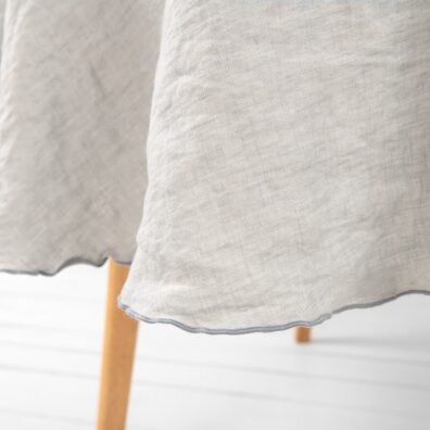 Pyöreä vaaleanharmaa pellava pöytäliina, koristeellinen tiheä sauma harmaata väriä