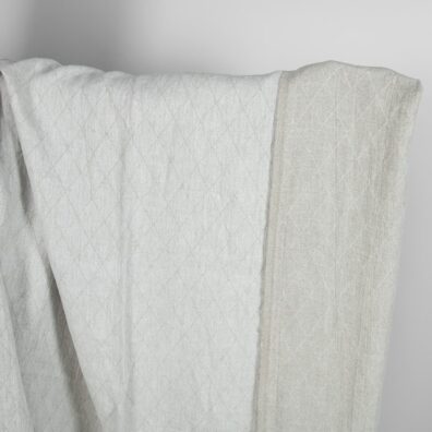 Vaaleanharmaa pellavakangas jossa on rombikuvio pesty