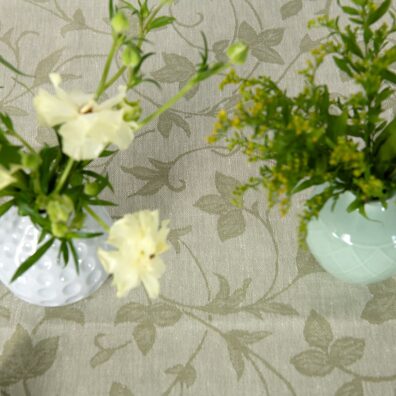 Puolipellava vihreä pöytäliina, oliivinvihreää ja vaniljaista (kellertävää) kudottua lankaa