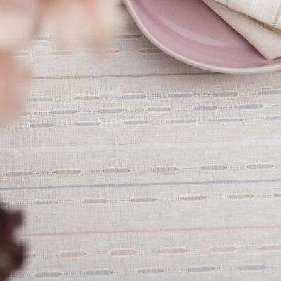 Valkoinen pöytäliina harmailla, vaaleanpunaisilla raidoilla varustettuna