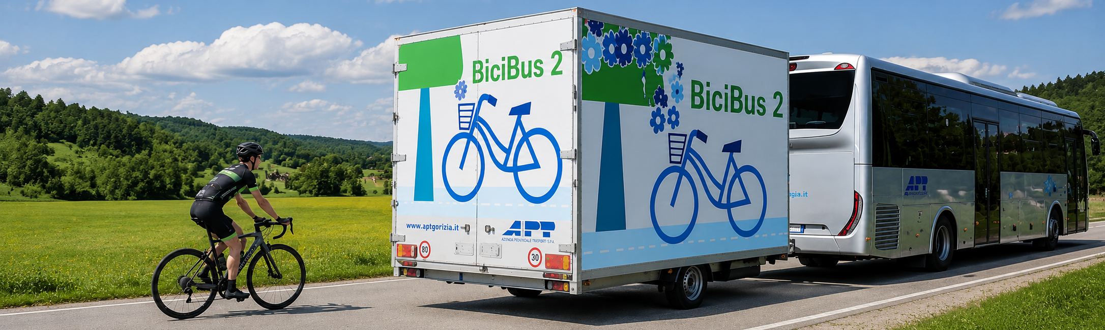 Autobus con logo APT e carrello portabici, seguito da un ciclista, con un prato sullo sfondo.