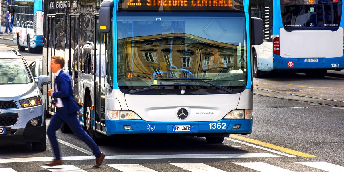 Linea urbana 21 di Trieste, con una persona in vestito blu che attraversa la strada di corsa.