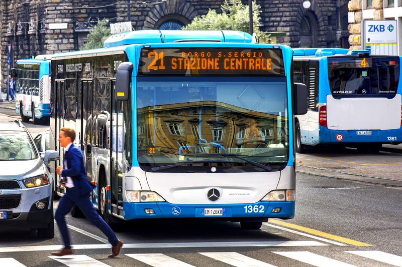 Linea urbana 21 di Trieste, con una persona in vestito blu che attraversa la strada di corsa.