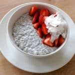 Een schaaltje chia pudding met plakjes aardbeien en kokosvlokken.