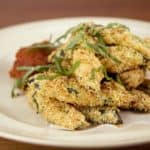 Een heerlijk portie knapperige courgette frietjes uit de oven met ketchup.