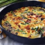 Koekenpan met gebakken frittata met asperges en champignons.