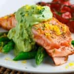 Een portie gegrilde zalm met groene asperges en avocadosaus.