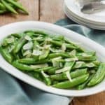 Ovenschaal met sugar snaps met gesmolten Parmezaanse kaas.