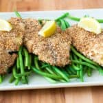 Tilapiafilets met krokante paneerlaag op een bedje van sperziebonen en citroenpartjes.