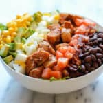 Schaal met heerlijke salade gemaakt van kip, bonen, tomaat, kip, avocado en dressing.