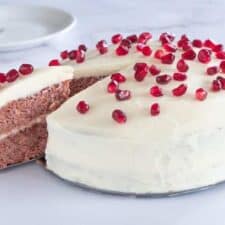 Red velvet cake met frosting en granaatappelpitjes.