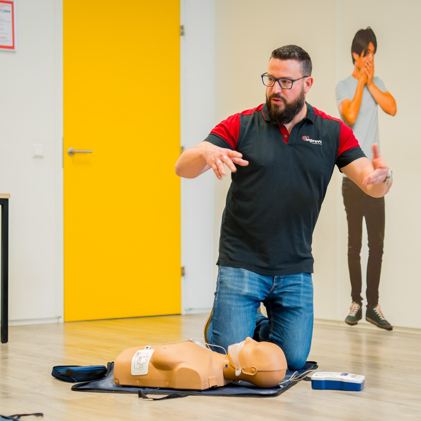 Instructeur geeft uitleg tijdens een BHV-training met reanimatiepop en AED