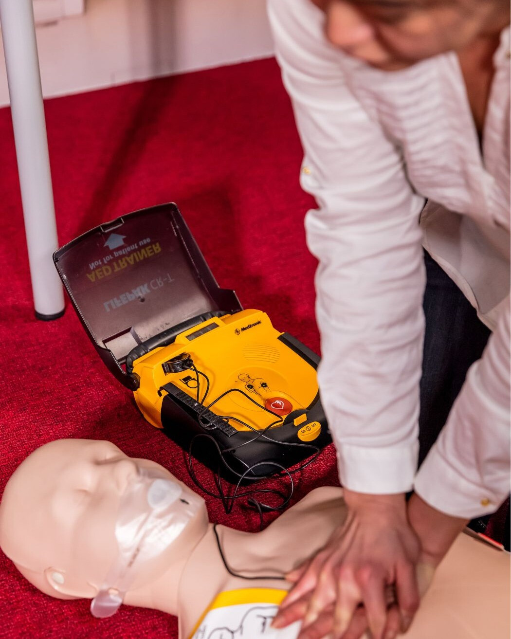 Medewerkers leren borstcompressies en AED gebruik tijdens een reanimatiecursus.