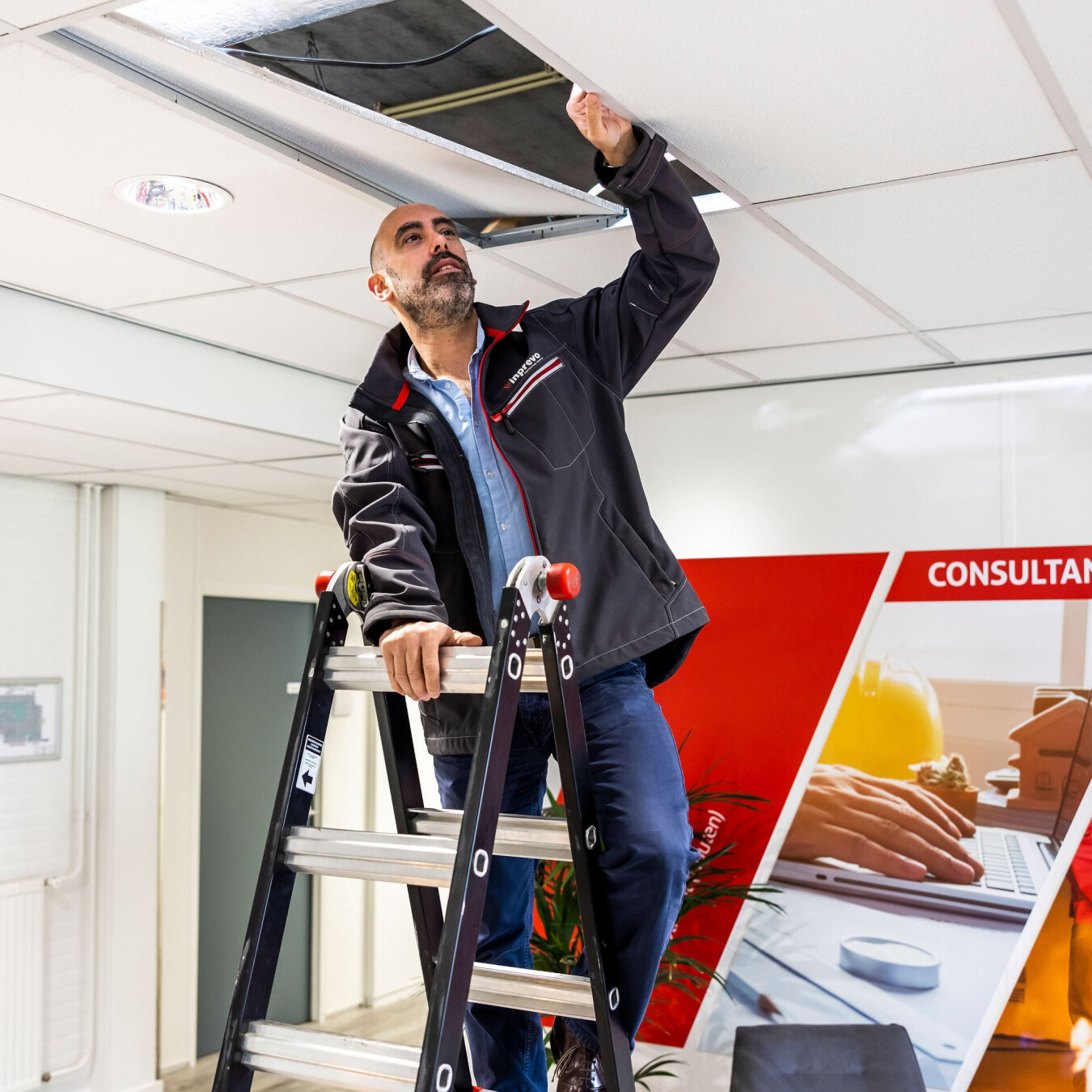 Inprevo-specialist controleert de brandveiligheid boven een systeemplafond
