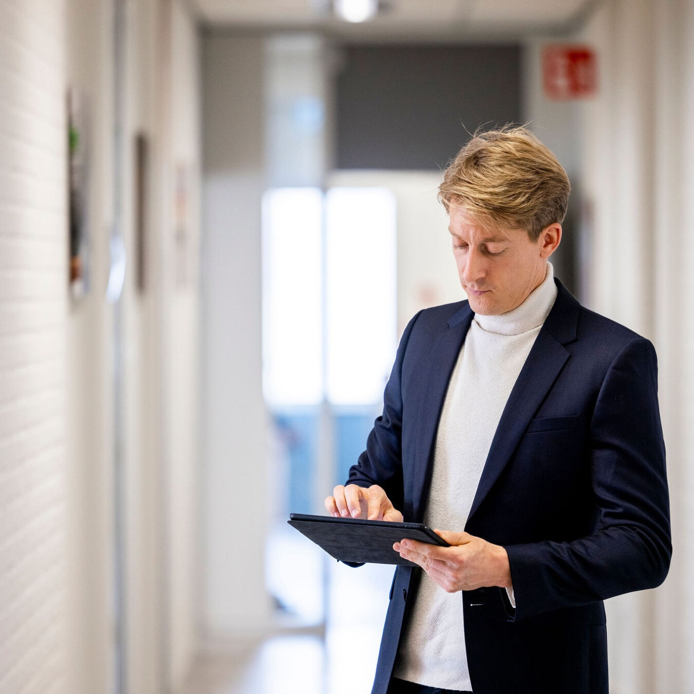 Adviseur bekijkt informatie op een tablet in een gebouwgang