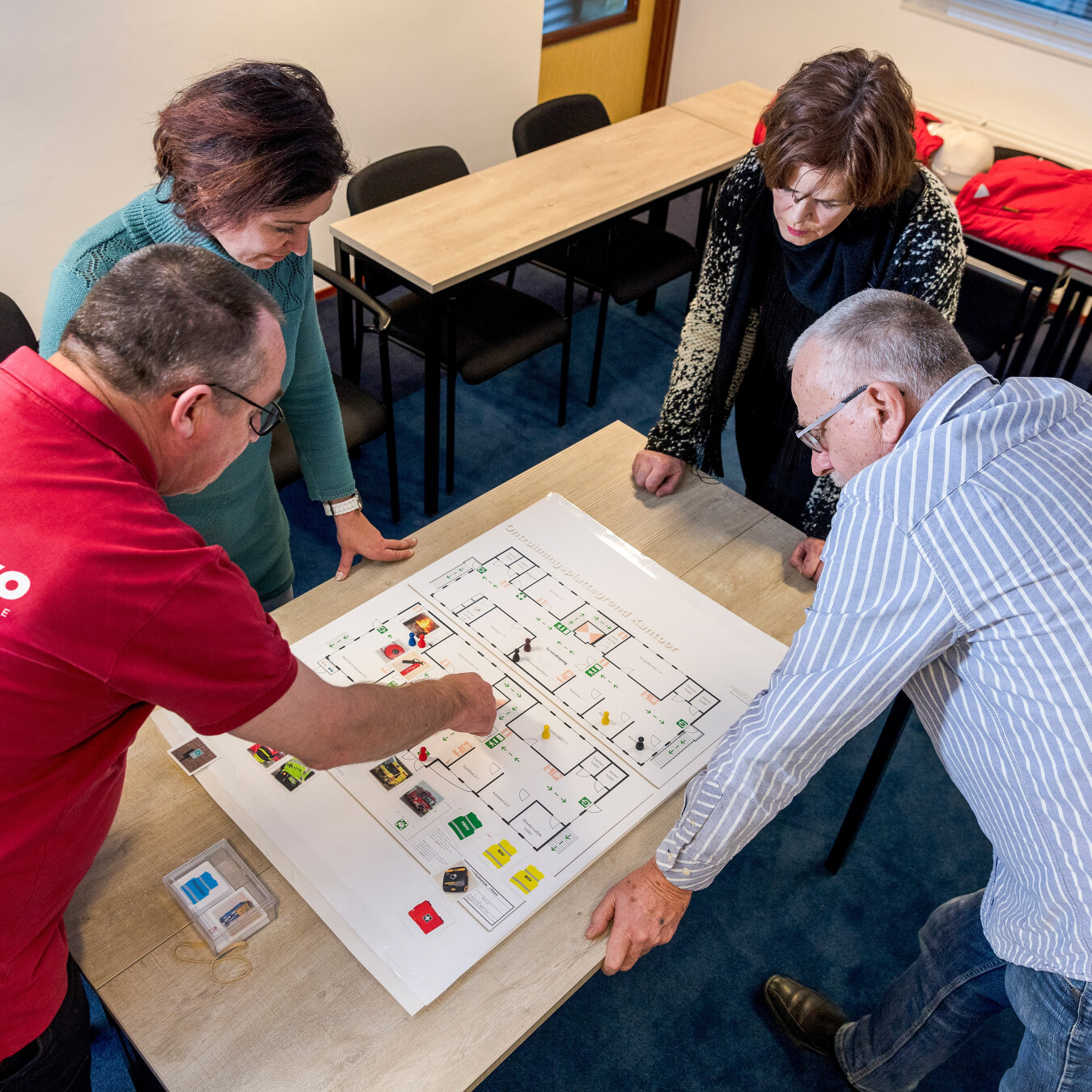 Medewerkers bespreken samen vluchtroutes en voorzieningen op een gebouwplattegrond