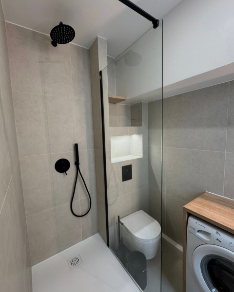 Salle de bain moderne et fonctionnelle avec douche à l’italienne, meuble sur mesure et robinetterie noire