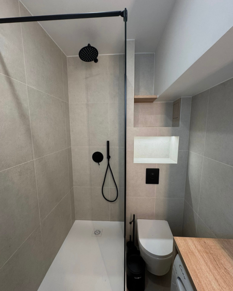 Salle de bain moderne et fonctionnelle avec douche à l’italienne, meuble sur mesure et robinetterie noire
