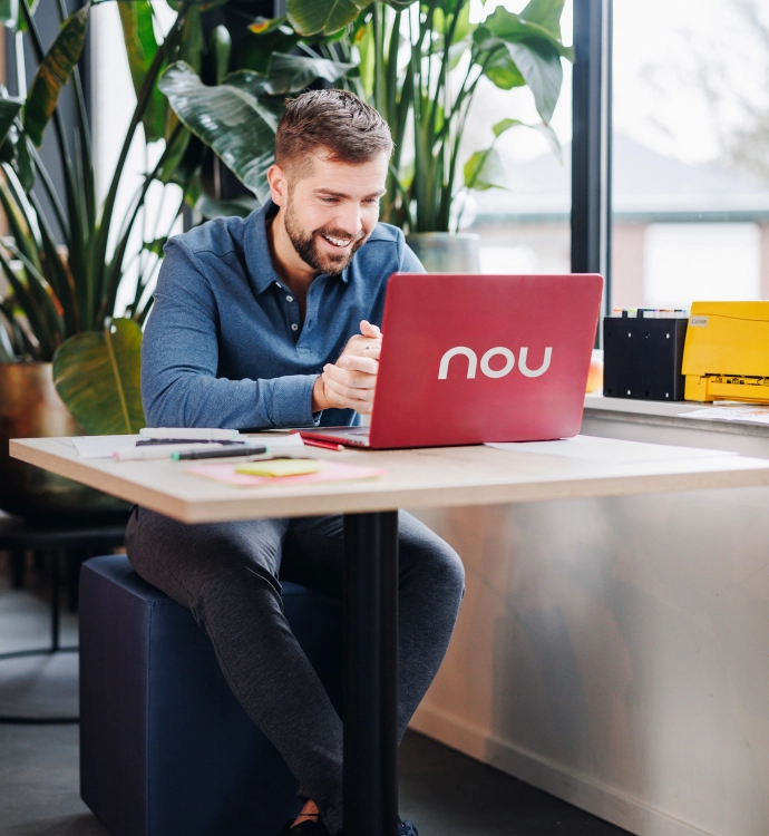 Persoon die lachend achter zijn laptop zit.