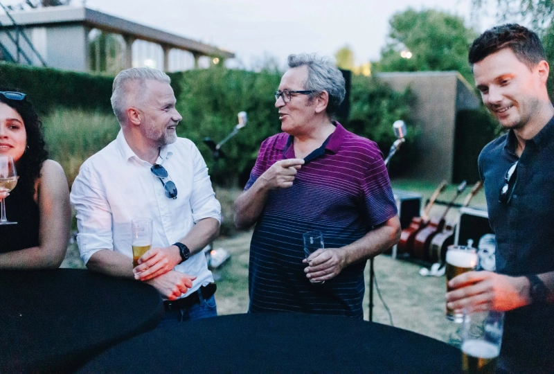 4 mensen die rondom een statafel staan met een drankje op een bedrijfsfeest.