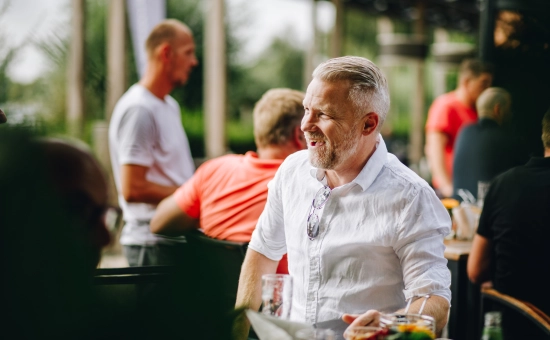 Een man die lachend aan tafel zit op een bedrijfsfeest.