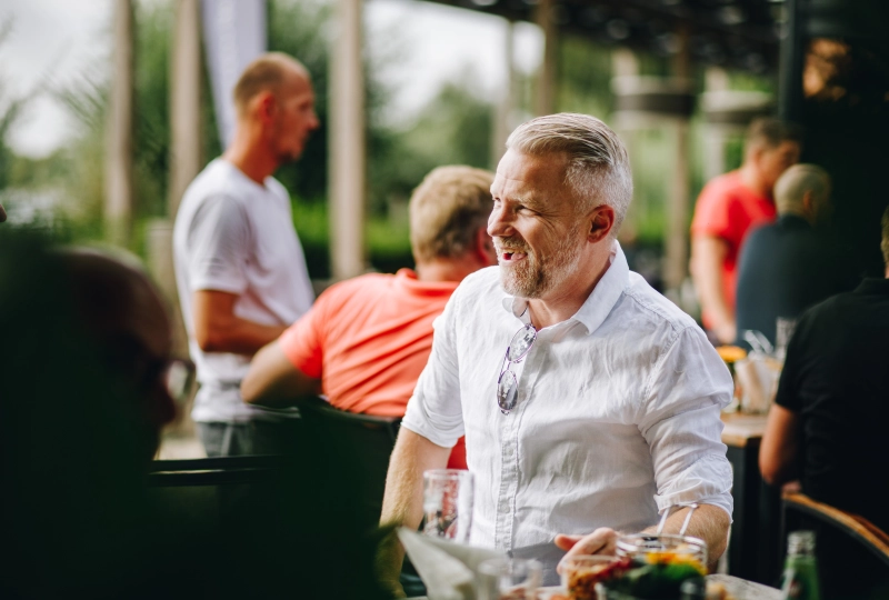 Een man die lachend aan tafel zit op een bedrijfsfeest.