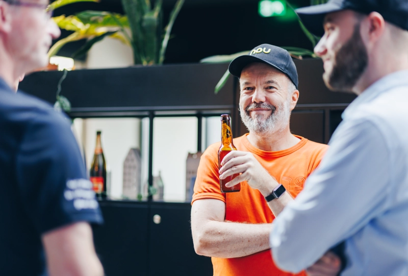 Lachende collega met Nou pet op en een biertje