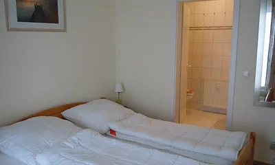 Das Schlafzimmer ist mit einem Doppelbett ausgestattet. Von hier aus gelangt man ins Bad.