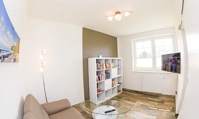 zweiter Wohnbereich mit Couch, TV und Auswahl an Büchern und Spielen