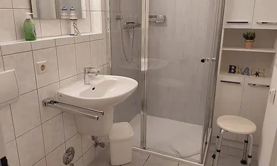 Geräumiges, weißes Duschbad mit Ablagemöglichkeiten, zahlreiche Haken für Handtücher und Duschhandtuchstange.usw. . 