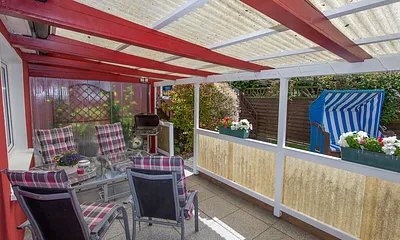 Umzäuntes Ferienhaus mit überdachter Terrasse.