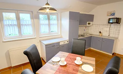 Komplett ausgestattete offene Einbauküche (Ceranfeld mit 4 Kochzonen, Grill- und Backautomat, Geschirrspüler, Toaster, Kaffeemaschine, Wasserkocher, Mikrowelle, Kühlschrank mit Gefrierfach, Geschirr).