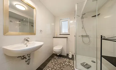 Das schicke Bad mit Echtglasdusche, Handtuchtrockner, Waschbecken, WC und Fenster.