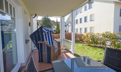 Geräumige Terrasse mit Süd-Westlage, großem Tisch, fünf Stühle und einem Strandkorb.