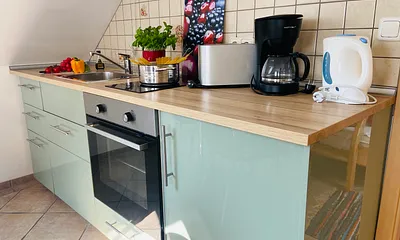 Essplatz mit Küchenzeile (Ceranfeld, Backofen, Kühlschrank, Toaster, Kaffeemaschine,  Wasserkocher, Geschirr usw.), Blick in das Kinderzimmer