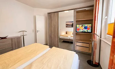 Schlafzimmer mit Doppelbett und zweitem Fernseher