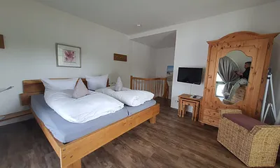 Schlafzimmer im ersten Obergeschoss mit Fernseher und Balkon