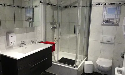 Duschbad mit Dusche (100x100), Toilette, Handtuchhalter, 3D Spiegel, Waschbecken, Schrank für mitgebrachte Gegenstände, Fön, Schminkspiegel, Hocker mit Schmutzwäschebehälter, Personenwaage