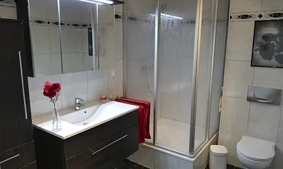 Duschbad mit Dusche (100x100), Toilette, Handtuchhalter, 3D Spiegel, Waschbecken, Schrank für mitgebrachte Gegenstände, Fön, Schminkspiegel, Hocker mit Schmutzwäschebehälter, Personenwaage