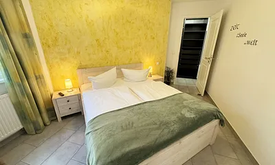 Schlafzimmer mit Doppelbett (1,60 m x 2,00 m), kleiner Flachbildschirm, Nachttischkonsolen, begehbarem Kleiderschrank und Insektenschutzgitter