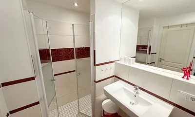 Badezimmer mit ebenerdiger Dusche, Waschbecken, WC, Fön, Kosmetikspiegel und Handtuchheizkörper