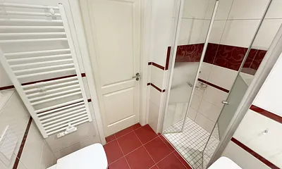 Badezimmer mit ebenerdiger Dusche, Waschbecken, WC, Fön, Kosmetikspiegel und Handtuchheizkörper