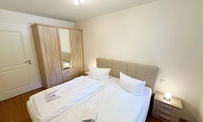 Schlafzimmer mit einem Boxspringbett (1,80 m x 2,00 m), Ablagefläche, Kleiderschrank und Insektenschutzgitter