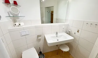 Badezimmer mit ebenerdiger Dusche, Waschbecken, WC und Handtuchtrockner