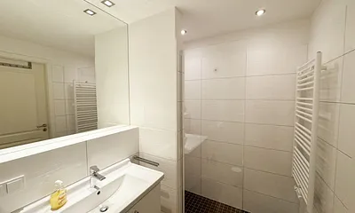 Badezimmer mit ebenerdiger Dusche, Waschbecken, WC und Handtuchheizkörper