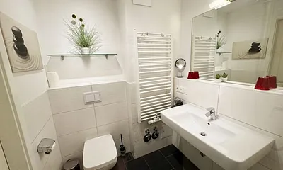 Badezimmer mit ebenerdiger Glasdusche, Fön, Waschbecken, WC und Handtuchtrockner
